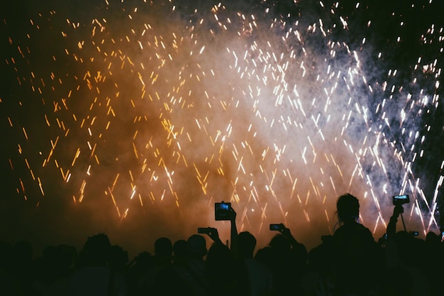 Lage hoek van silhouetten van mensen die's nachts vuurwerk fotograferen