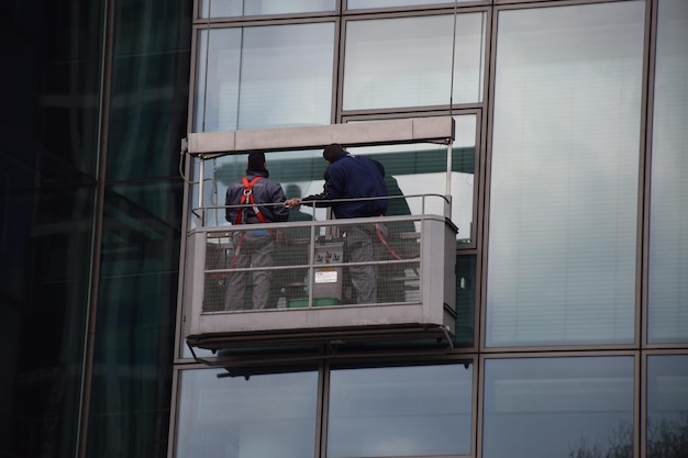 Lage hoek van vensterwasmachines die een glasgebouw schoonmaken