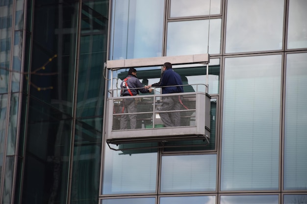 Lage hoek van vensterwasmachines die een glasgebouw schoonmaken