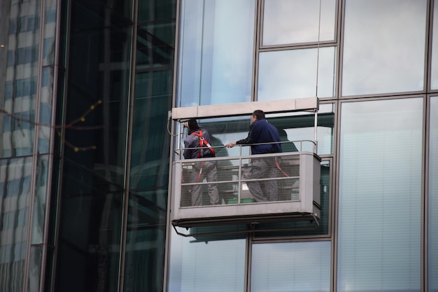 Lage hoek van vensterwasmachines die een glasgebouw schoonmaken
