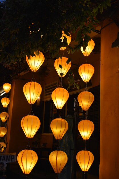 Lage hoek van verlichte lantaarns die tegen een gebouwde structuur hangen