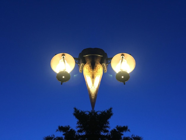 Foto lage hoek van verlichte straatverlichting tegen een heldere blauwe hemel