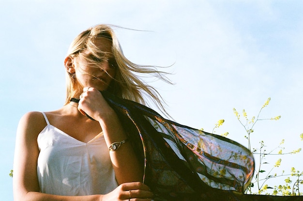 Lage hoek van vrouw met sjaal tegen de lucht op een winderige dag