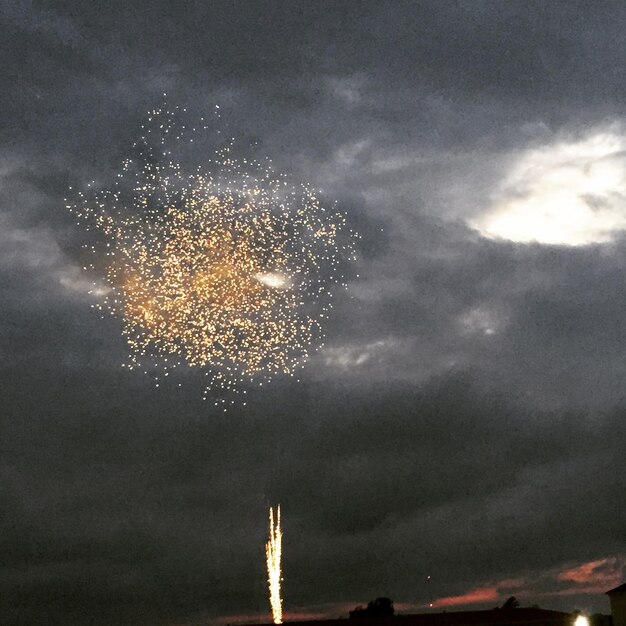 Foto lage hoek van vuurwerk op een bewolkte hemel bij zonsondergang