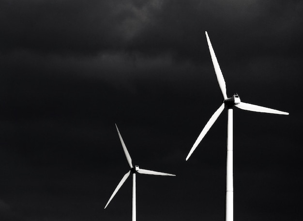 Foto lage hoek van windturbines tegen bewolkte lucht