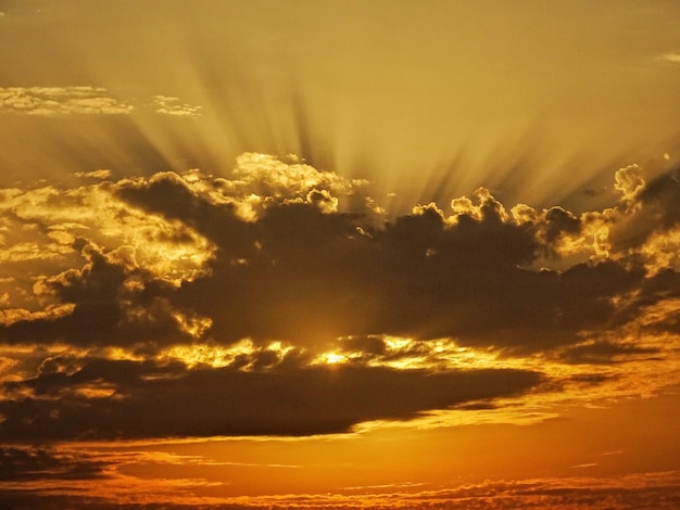 Foto lage hoek van zonlicht dat tijdens de zonsondergang door wolken stroomt