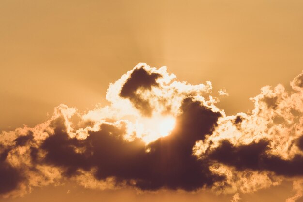 Foto lage hoek van zonlicht dat tijdens de zonsondergang door wolken stroomt