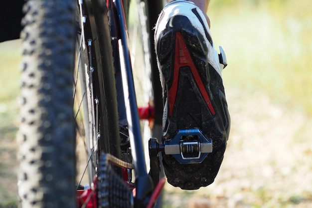 Lage hoek weergave. Detail van de voeten die van de fietsermens bergfiets berijden op openlucht. Trail op landweg. Alleen het been is zichtbaar.