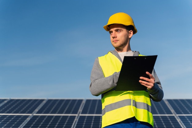 Lage hoekmening van de handschriftagenda van de man, maak aantekeningen op het industriegebied van zonnepanelen Groene energieconcept