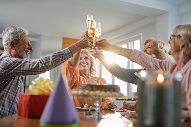 Lage hoekmening van gelukkige volwassen vrienden die verjaardag vieren en thuis roosteren met champagne