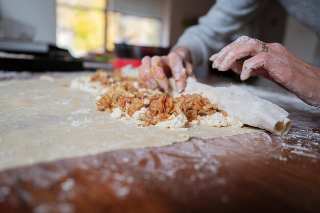 Lage hoekmening van vrouwelijke handen die zelfgemaakte apfelstrudel op een eettafel rollen.