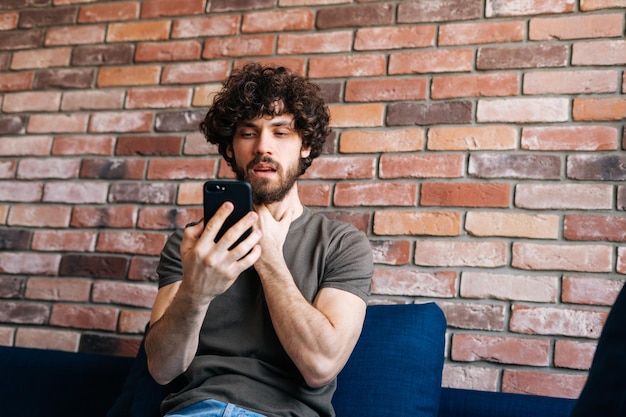 Lage hoekmening van zieke jonge mannelijke patiënt die via een videogesprek chat met een arts die een mobiele telefoon gebruikt vanuit huis