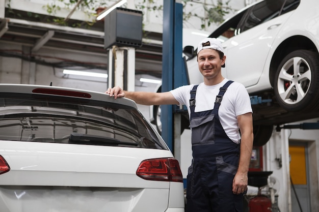 Lage hoekopname van een vrolijke autoreparateur die lacht naar de camera in zijn garage