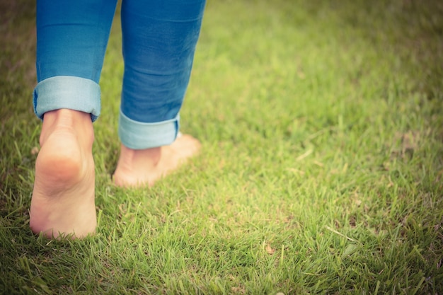 Lage sectie die van vrouw op grasrijk landschap lopen