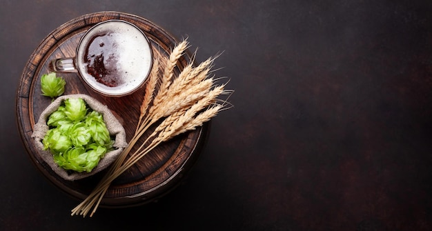 Lager beer mug hops and wheat on old wooden barrel