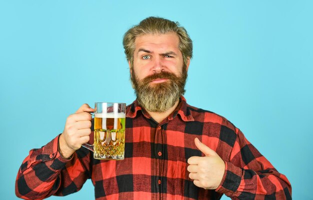 ラガービールリラックスしたハンサムな男がパブでグラスを楽しんでいるおいしいビールを飲みながら、パブのバーカウンターで生ビールを飲んだ後、新鮮な冷たいラガービールを期待しています