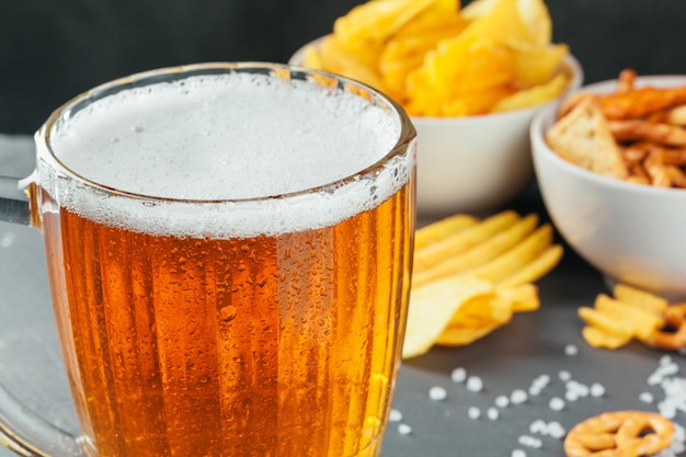 Lager beer and snacks on stone table. Cracker, chips side view