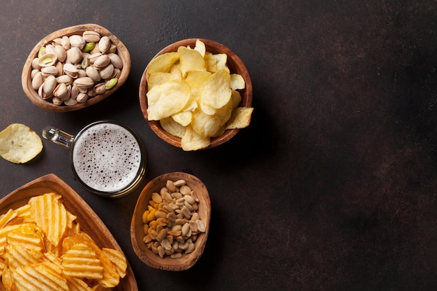 Lager beer and snacks on stone table. Nuts, chips. Top view with copyspace