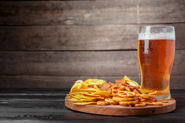 Lager beer and snacks on wooden table. 