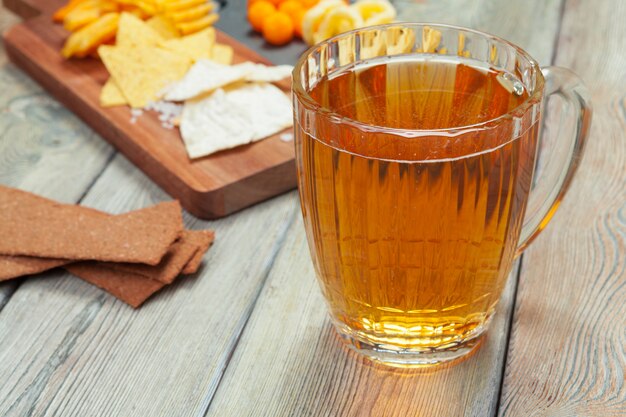 Lager beer and snacks on wooden table.