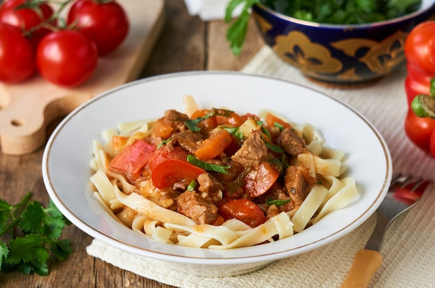 Lagman noodles with beef meat and vegetables in a white bowl