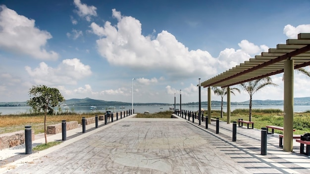 A lagoon with boats in the background a white horse eating a pergola and benches on the right a pergola and benches