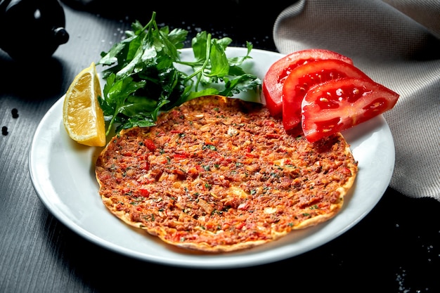 Lahmacun is een populair Turks gerecht. Dunne knapperige tortilla met lamsgehakt, tomaten en paprika op zwarte tafel