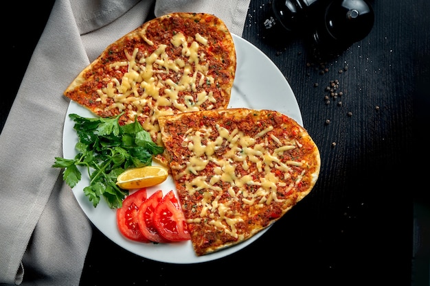 Lahmacun is a popular Turkish dish. Thin crispy tortilla with minced lamb, tomatoes and bell pepper on black