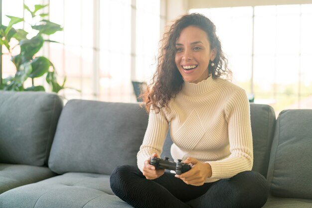 Laitin-vrouw die videogames speelt met handen met joystick op de bank thuis