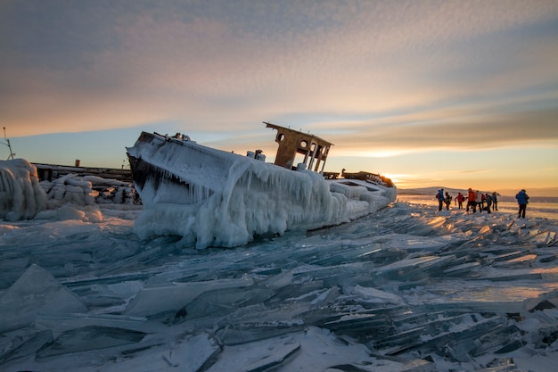 Lake Baikal at sunset, everything is covered with ice and snow, thick clear blue ice