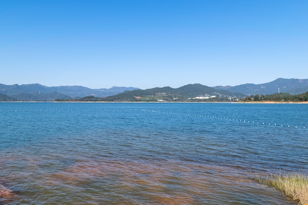 青い空の下の湖は青い水と赤い土地を持っています