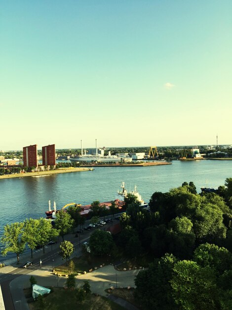 Lake by trees against clear sky in city