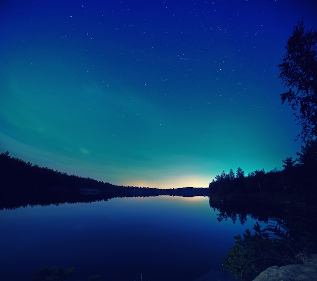 놀라운 별이 빛나는 하늘과 물에 반사가 있는 밤의 호수. 자연의 아웃도어는 어두운 배경을 여행합니다.
