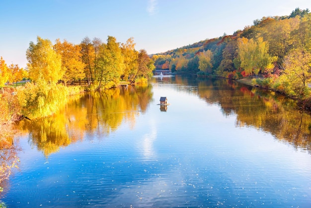 Lake in park with small house and autumn forest and trees