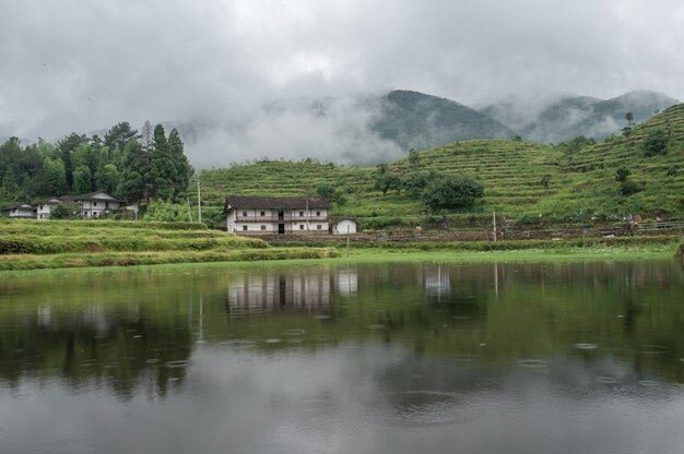 The lake reflected the mountain with houses and fog on the mountain