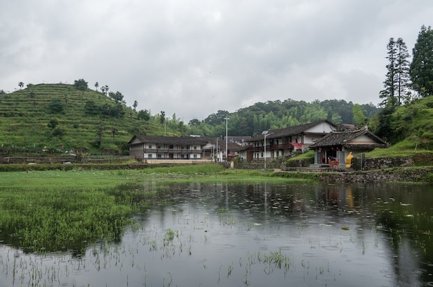 The lake reflected the mountain with houses and fog on the mountain