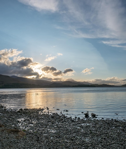 Lake side coast view with mountain background under cloudy evening twilight sky