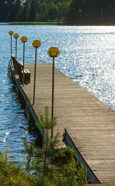 Lake summer view with forest on the edge and wooden pier ( Finland).