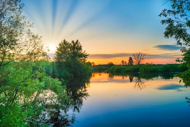 Lake water sunset and sun rays on nature landscape with sunset sky