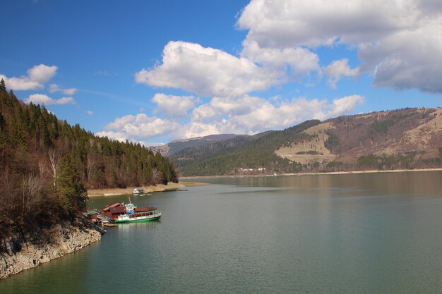 Photo a lake with a boat and a mountain in the background