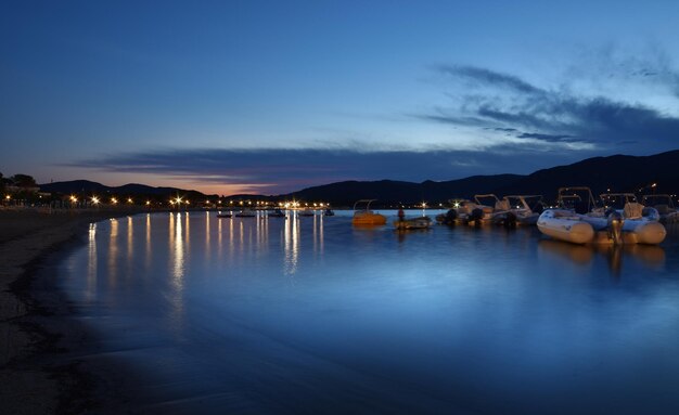 A lake with boats and a blue sky at night