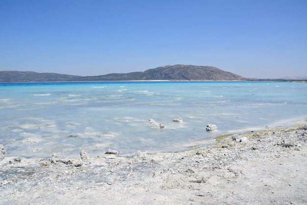 lake with light blue water and white sand in sunny day