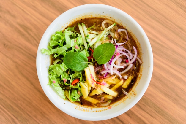 Laksa  is a spicy noodle soup on wooden table.