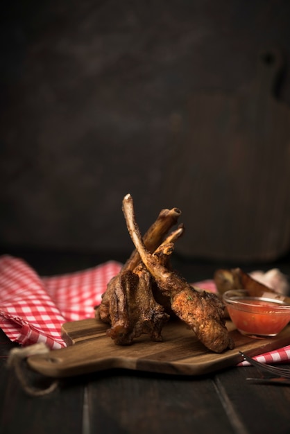 Фото Бараньи ребрышки на деревянной доске с соусом