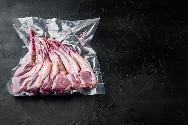 Lamb chops vacuumed for preservation or sous vide cooking set, on black stone background , with copyspace  and space for text