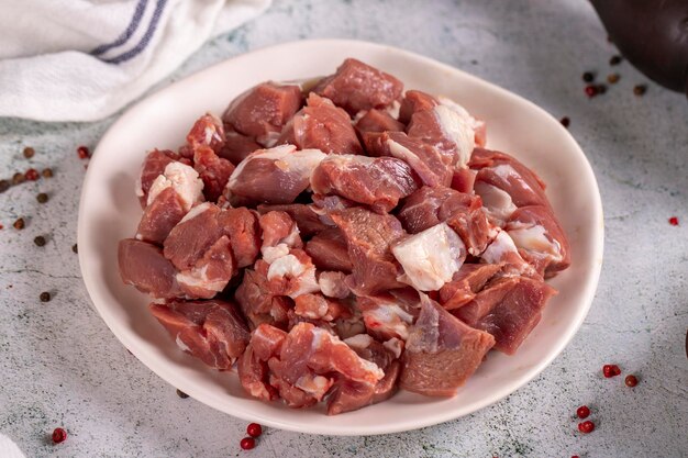 Foto carne di agnello in cubetti carne rossa tritata in un piatto su un pavimento di pietra prodotti di macellazione da vicino