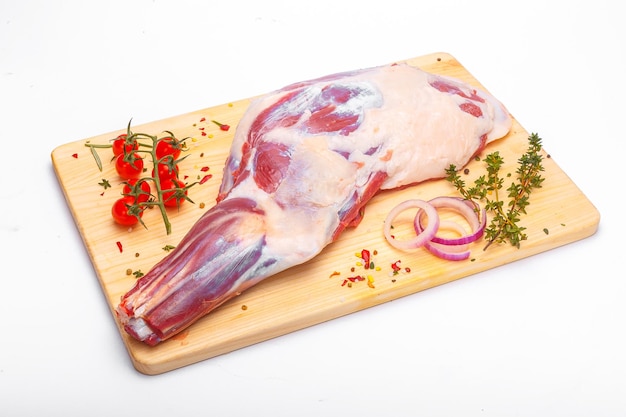 A lamb on a cutting board with red onions and tomatoes.