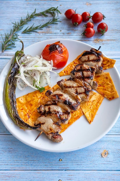 Lamb Delight grilled on a blue wood background with roasted tomatoes onions and peppers