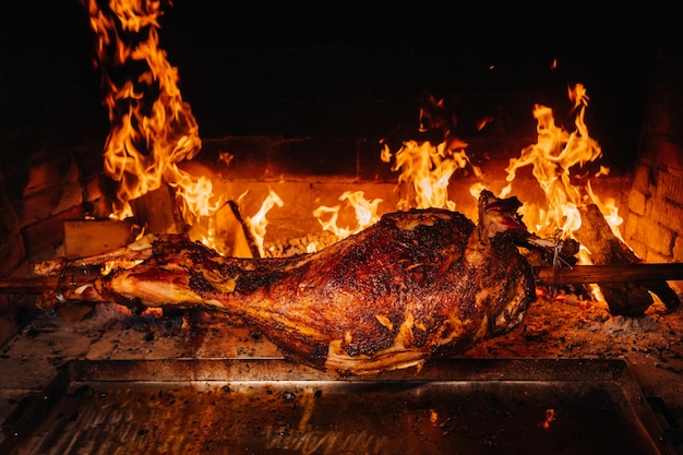 The lamb is cooked entirely on a spit on the fire cooking