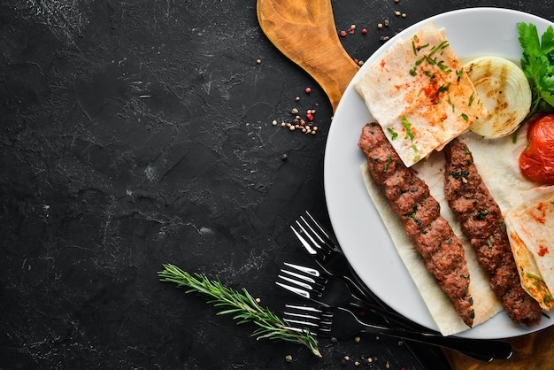 Lamb Kebab Pita bread and spices On a black background Top view